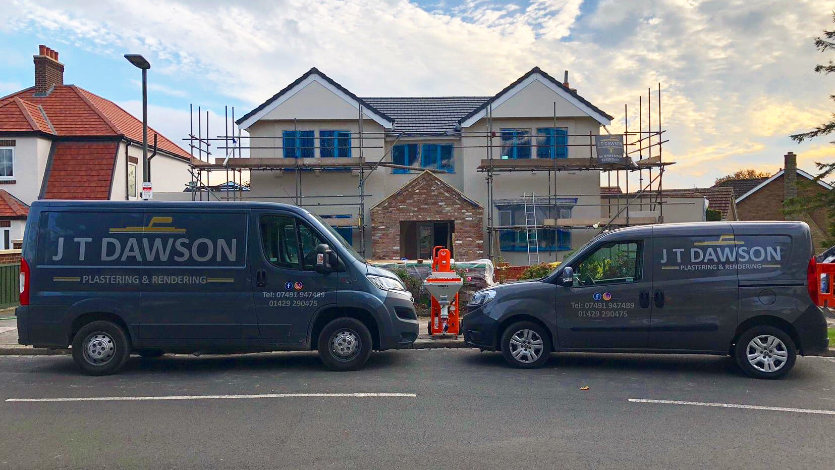 Two J T Dawson Plastering & Rendering vans parked outside a house being built