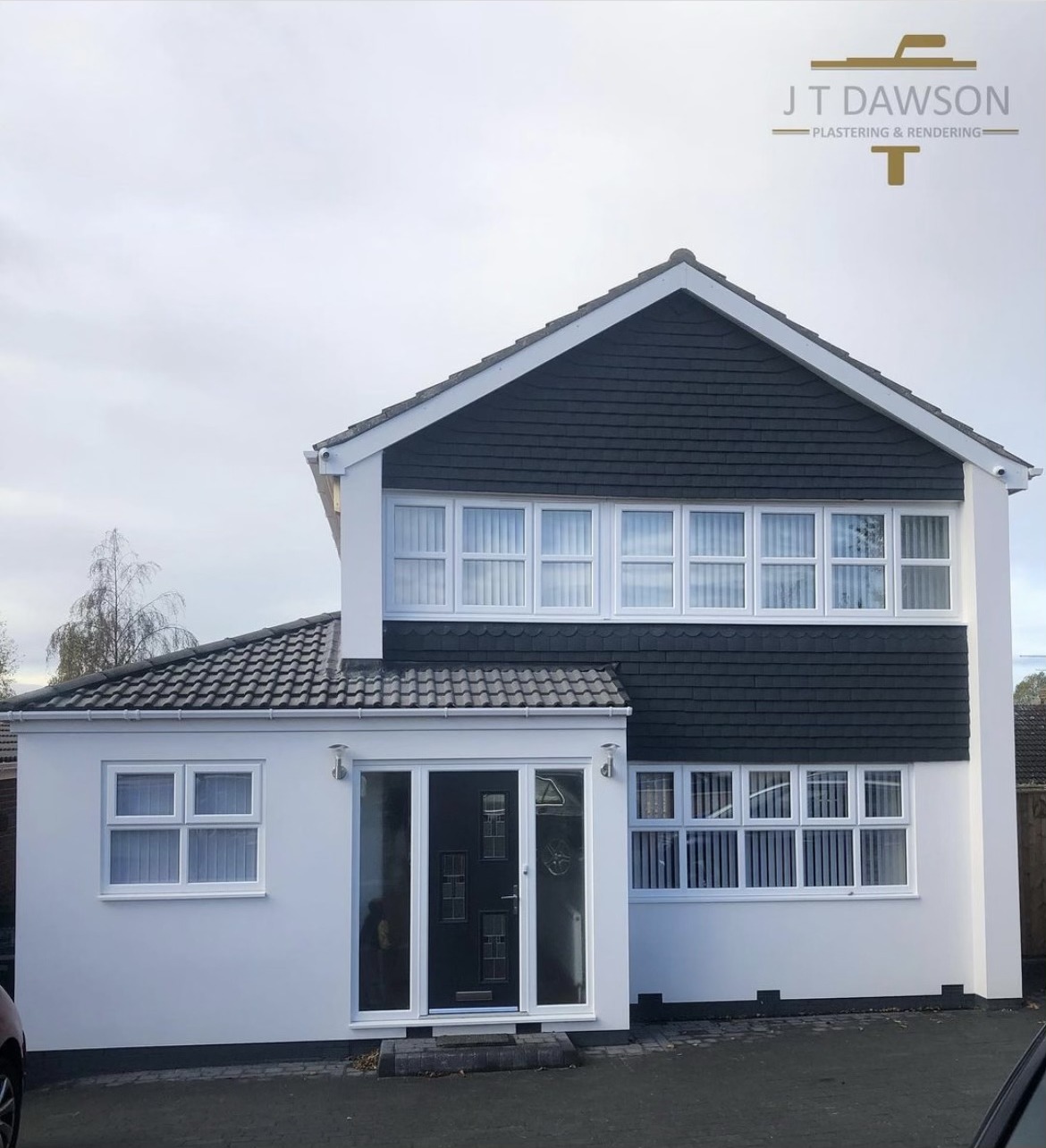 White-rendered house with dark cladding on the upper gable, by J T Dawson