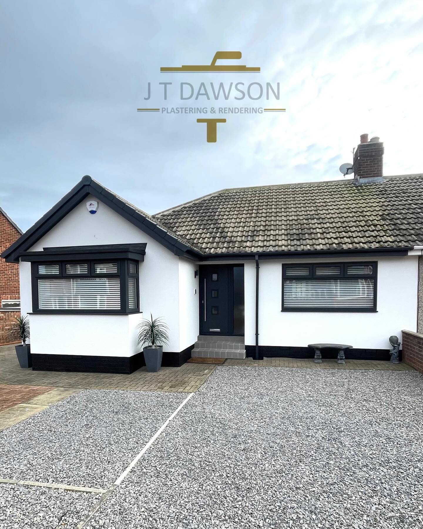 White-rendered bungalow with a black plinth and gravel drive, by J T Dawson