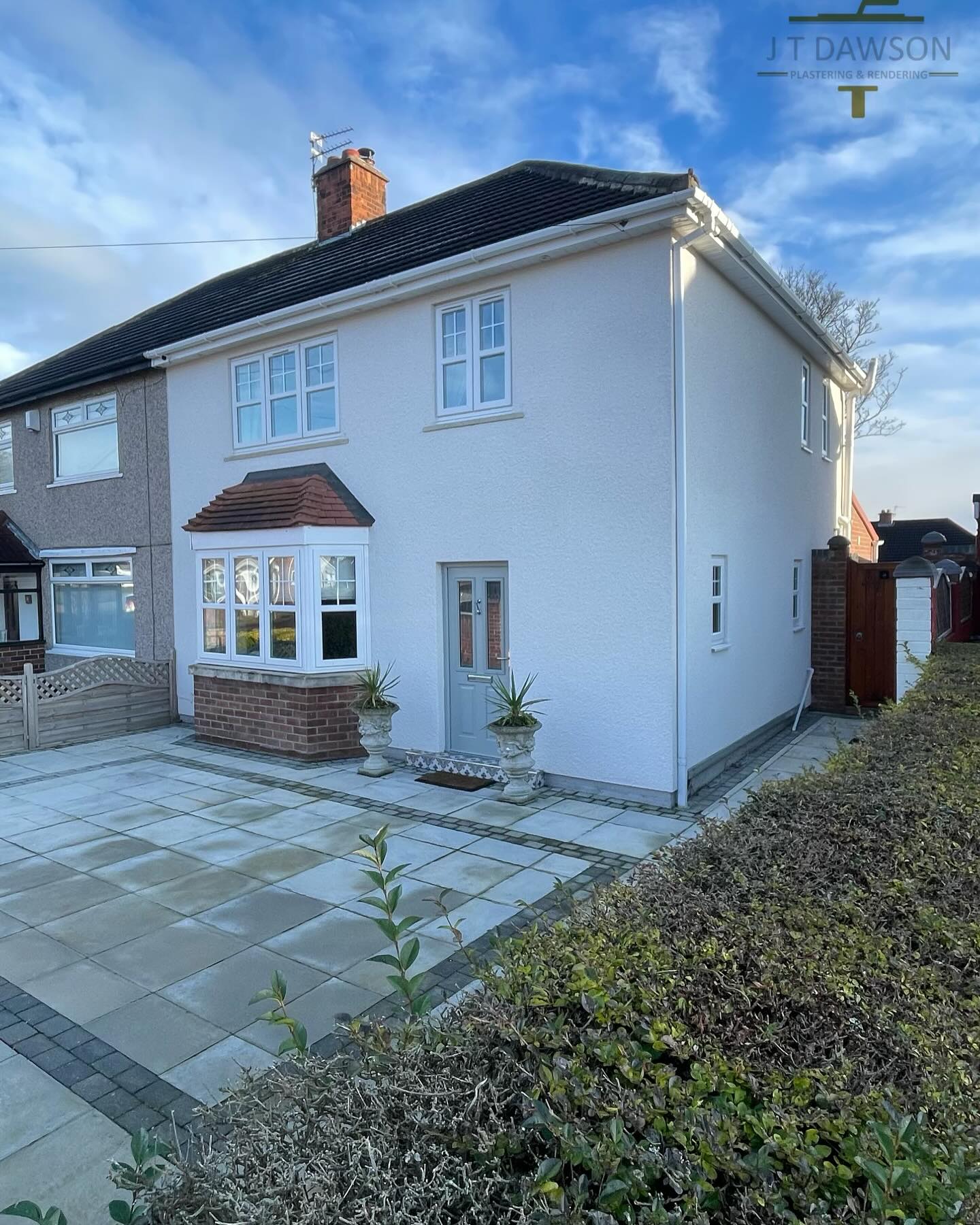 Semi-detached house in white render with a new patio, by J T Dawson